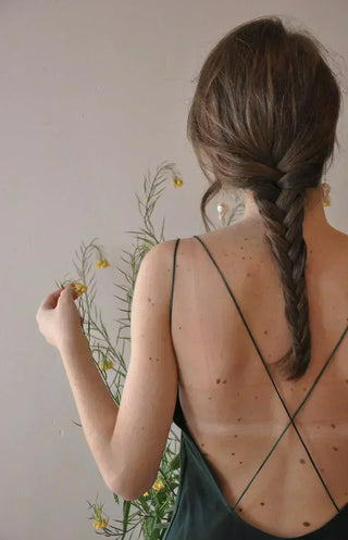 Back view of a woman with beautifully plaited hair, highlighting healthy, natural skin and the calming essence of gentle skincare
