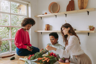 Three women preparing fresh vegetables together in a kitchen