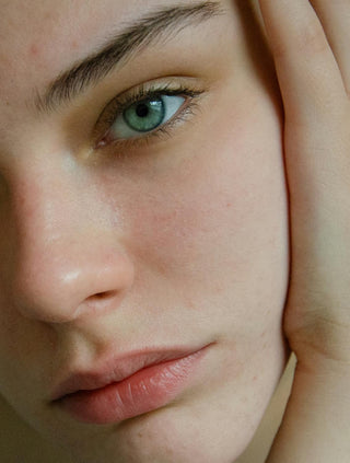 Close-up of a woman with green eyes and glowing skin, highlighting natural beauty and skincare