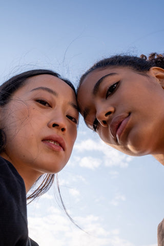 Two people looking down at a camera with a blue sky behind