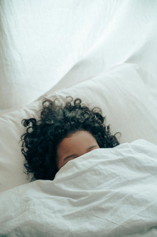 Person with bed sheets over their head