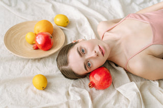 woman on white linen with pomegranates and lemons, evoking a serene and modern mood